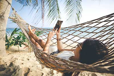  Happy woman using mobile phone in hammock