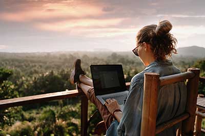 Young woman working at the computer in cafe on the rock