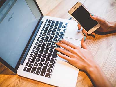 Close-up of a hand using laptop on a wooden table