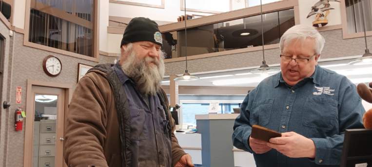 Daryl Tomczak showing loan officer John Wesely his father's old savings book